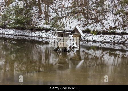 La neve e il laghetto in inverno e alimentatori per anatre e di riflessione Foto Stock