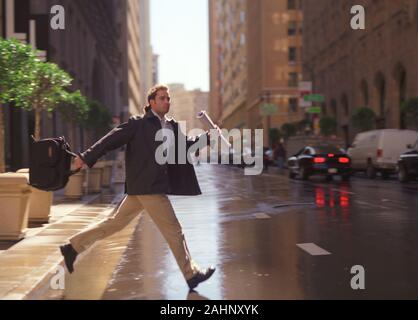 Vista laterale di un giovane uomo che corre attraverso una strada. Foto Stock