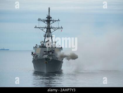 Un U.S. Navy Arleigh Burke-class guidato-missile cacciatorpediniere USS Paul Hamilton incendi un contrassegno 45, 5 pollici pistola durante un'esercitazione a fuoco mentre in corso Dicembre 7, 2019 nell'Oceano Pacifico. Foto Stock