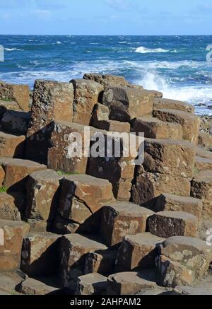 Giant's Causeway, close-up di colonne di basalto con onde che si infrangono sulla loro, County Antrim, Irlanda del Nord, Regno Unito. Foto Stock