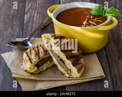 Una vista ravvicinata di una ciotola di zuppa di pomodoro con una grigliata di tostare panini panino pronto per mangiare. Foto Stock