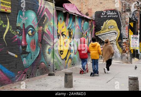 La donna e i bambini passando la street art e graffiti dipinti su esterno di edifici in Candelaria distretto di Bogotà, Colombia Foto Stock