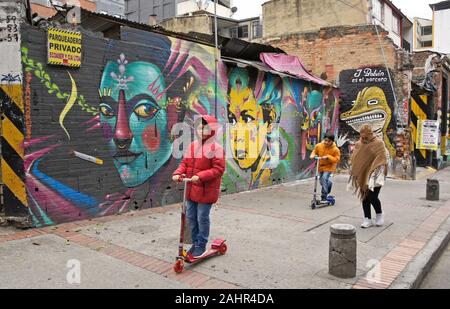 La donna e i bambini passando la street art e graffiti dipinti su esterno di edifici in Candelaria distretto di Bogotà, Colombia Foto Stock