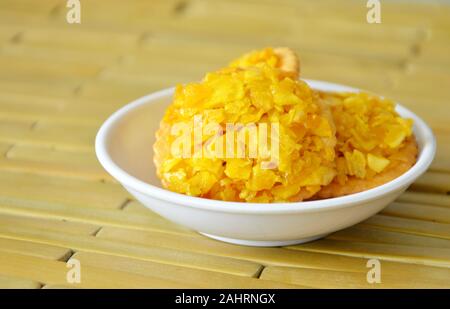 Crackers topping croccante frutta jack e di arachidi con caramello sulla piastra di bambù Foto Stock