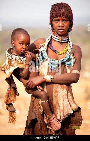 Madre con un bambino che indossa la decorazione della pelle animale e le collane del guscio, tribù di Hamer, valle di Omo, Etiopia Foto Stock