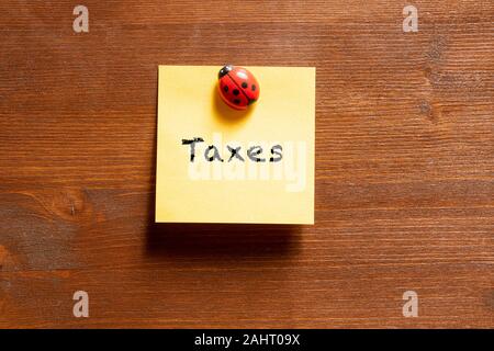 Un memo colorati foglio con la scrittura di tasse Foto Stock