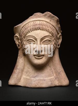 Antico insediamento Etrusco. Votive (dono) nella forma di una testa di donna. 500 BC. Veio. terracotta, il supplicant di pigmento posto teste votive in templi di accompagnare le richieste e le offerte di ringraziamento agli dèi. Artigiani stampi usati per produrre le immagini di entrambi gli uomini e le donne. In esempi più fini, come ad esempio questa testa, un attrezzo appuntito è stata utilizzata per affinare gli elementi del viso e capelli prima che l'oggetto è stato cotto nel forno. Tracce di pigmento suggeriscono che i capelli è stata originariamente dipinta di un colore rosso brillante. Orecchini una volta appeso da fori nelle orecchie. Foto Stock