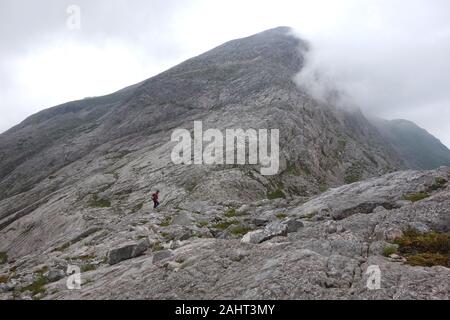 Lone uomo a camminare su di una ripida lisce lastre di quarzite scozzese della montagna un Corbett Ruadh-Stac in Strathcarron, Highlands scozzesi, Scotland, Regno Unito. Foto Stock