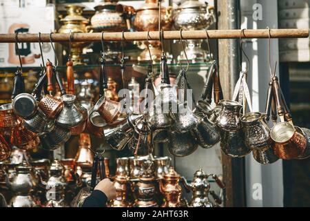 Vendita di tradizionali turchi turchi per fare il caffè al mercato turco a Istanbul. Il venditore prende uno Turk Foto Stock