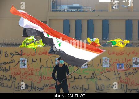 Baghdad in Iraq. 01 gen, 2020. Un manifestante detiene una bandiera irachena durante il sit-in contro di noi mortali incursioni aeree su siti di una milizia sciita di fronte all'ambasciata americana. Lutto iracheno martedì assaltata la costruzione dell'Ambasciata degli Stati Uniti a Baghdad pesantemente fortificata Zona verde. Credito: Ameer Al Mohmmedaw/dpa/Alamy Live News Foto Stock