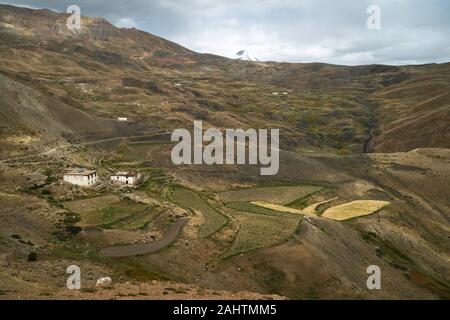 Paesaggio di rotolamento con poche case sparse circondato da Himalaya in Spiti Valley vicino a villaggio Tashigong, Himachal Pradesh, India. Foto Stock