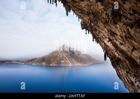 Uomo di arrampicata percorsi impegnativi in drammatico Grande Grotte grotta sul isola di Kalymnos. Foto Stock