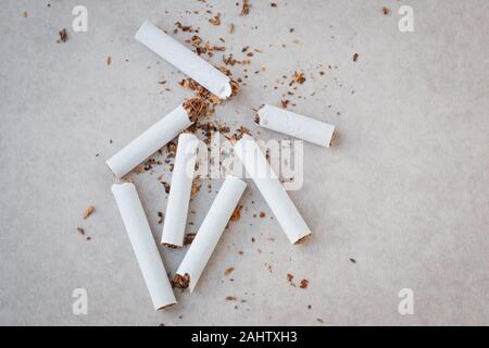 Sparse schiacciate le sigarette e il tabacco su uno sfondo neutro. Cessazione del fumare concept Foto Stock