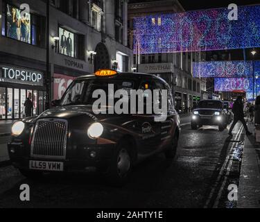 Nuovo anno su Oxford Street con la mitica London Black Cab. Foto Stock