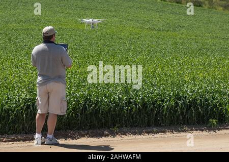 Pilota comandante dei velivoli senza pilota drone di raccogliere dati su terreni agricoli del paese campo. Foto Stock