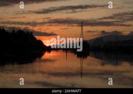 Un tramonto sul Bonneville Dam sul fiume Columbia, Oregon, completare con alcune belle riflessioni sull'acqua. Foto Stock