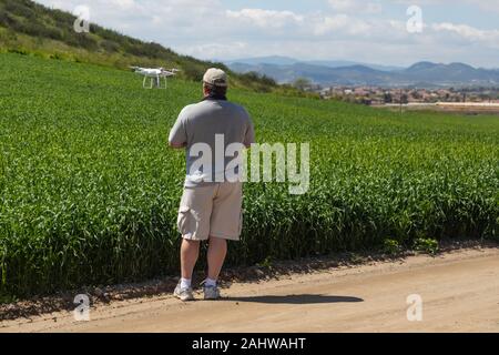 Pilota comandante dei velivoli senza pilota drone di raccogliere dati su terreni agricoli del paese campo. Foto Stock