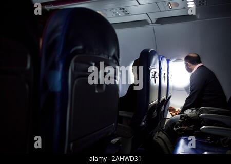 Uomo in sedia a bordo di un aereo guardando fuori dalla finestra Foto Stock