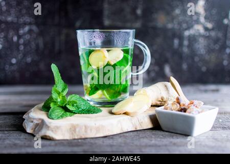 Il tè con la menta fresca e lo zenzero pezzi su una tavola di legno. Ideale come di un eye-catcher. Foto Stock