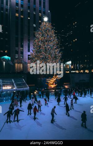 Albero di natale e la pista di pattinaggio su ghiaccio al Rockefeller Center di notte in Midtown Manhattan, a New York City Foto Stock