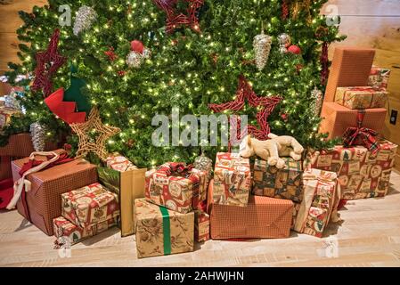 Le decorazioni di Natale e regali sotto un grande albero di Natale. Foto Stock