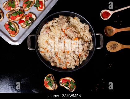 Ciotola wok con il tradizionale cibo piccante chiamato pilaf, su sfondo di legno. Cucinato con agnello fritto, riso, aglio, carota e uvetta. Foto Stock