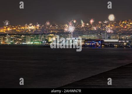 Serie di fuochi d'artificio al di sopra di grande area residenziale paesaggio di notte. Il veglione di Capodanno fuochi d'artificio a Salonicco, Grecia visto da il lungomare della città. Foto Stock