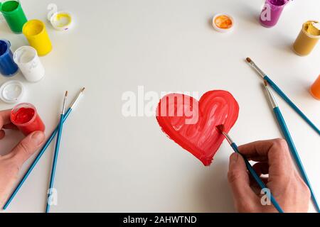 Vista superiore della donna dipinto a mano cuore rosso su sfondo bianco, artistico occupazione creativa, il concetto di amore Foto Stock