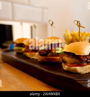 Burger di piccole dimensioni su un piatto di legno vicino fino Foto Stock