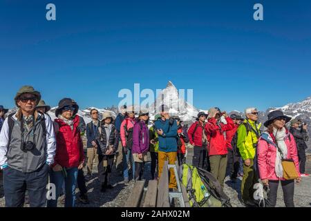 Un gruppo di turisti cinesi in visita Gornergrat prendere uno sguardo intorno al monte Cervino. Svizzera Foto Stock