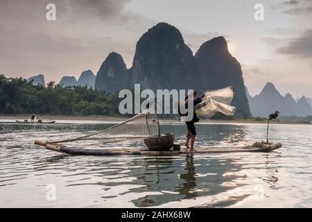 Rete da ballo, pescatore al tramonto sul fiume li, villaggio di pescatori di Xingping, Guangxi, Cina Foto Stock