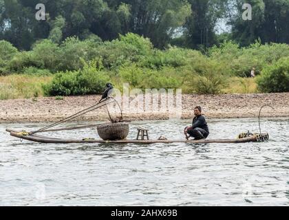 Pescatore comoriano che scende lungo il fiume li su una zattera di bambù, Xingping, provincia Guangxi, Cina Foto Stock