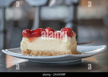 Vista dettagliata sezione Strawberry Cheesecake layer cake Dessert cibo su una piastra bianca in cafe focus blur sullo sfondo Foto Stock