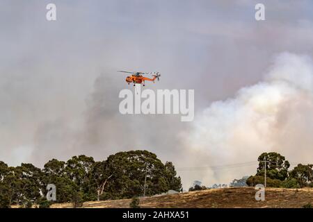 Erickson Air Crane elicottero N243AC (Sikorsky S-64) volare contro pennacchi di fumo durante la lotta contro gli incendi di bush in Victoria, Australia. Foto Stock