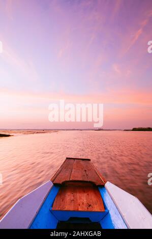 Thai barca dalla coda lunga centina anteriore in pacifica di Nong Harn lago, Udonthani - Thailandia. La barca di legno sotto la vibrante bellissima alba cielo sopra red lotus lake. Foto Stock