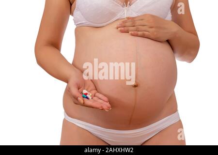 Donna incinta con una pillola in mano. Cure sanitarie durante la gravidanza. Gravidanza e supplementi di vitamina. Foto Stock