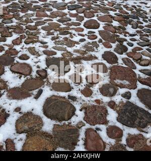 Vecchio acciottolato strada coperta di neve. Foto Stock