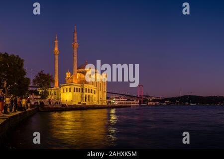 Le persone sono la raccolta presso la moschea di Ortaköy, Ortaköy Camii, situato sul Bosforo, il confine continentale tra Europa e Asia, illuminata di notte Foto Stock