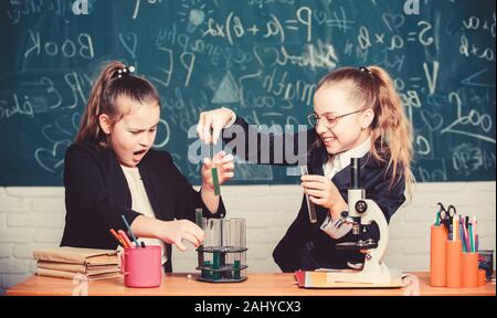 Microscopio e provette per la prova sul tavolo. Esperimento educativo concetto. Prestare attenzione a eseguire la reazione chimica. Conoscenze di base di chimica. Ragazze studio chimica. Fare studiare la chimica interessante. Foto Stock