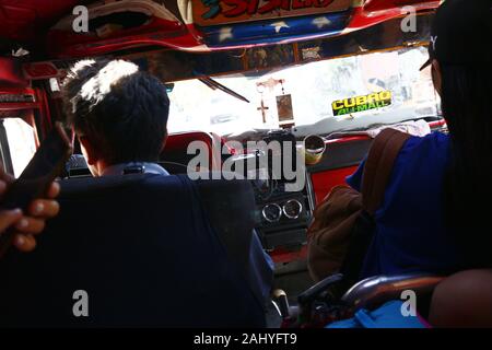 Antipolo City, Filippine - 27 dicembre 2019: il conducente ed i passeggeri all'interno di una jeep di passeggeri che viaggiano in una giornata di sole. Foto Stock