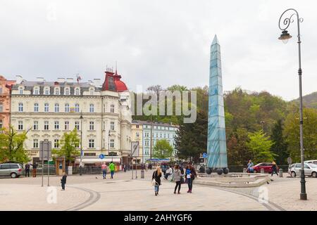 Karlovy Vary, Repubblica Ceca - 5 Maggio 2017: la gente a piedi vicino Masaryka-fontana Obelisco a nuvoloso giorno di primavera Foto Stock