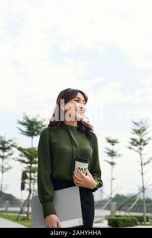 Donna asiatica di prendere una pausa caffè presso il parco della città. Bella giovane imprenditrice ritratto. Foto Stock