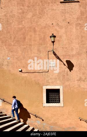 Parete di color ocra, lampione e scale con uomo salendo a Musei Capitolini situato in Piazza del Campidoglio. Roma, Italia. Il 9 ottobre 2019. Foto Stock