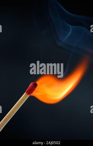 Confronto di legno bastone con testa di colore rosso acceso e la masterizzazione luminoso grande fiamma di fuoco con fumo su sfondo nero. Foto Stock
