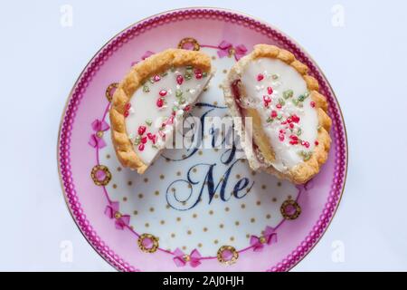 Signor Kipling Bakewells festosa bakewell tart estremamente buone torte tagliato a metà sulla piastra con Try me sul set su sfondo bianco Foto Stock