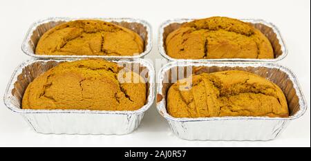 Quattro polpettine di pane appena sfornato pane di zucca in contenitori di alluminio con uno sfondo bianco. Foto Stock