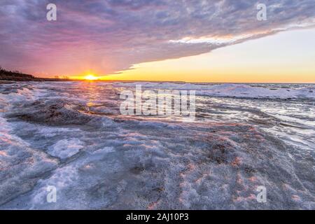 Michigan inverno Lago paesaggio. Raggi di sole illuminano la congelati icy costa del Lago Huron Michigan sui Grandi Laghi costa. Foto Stock