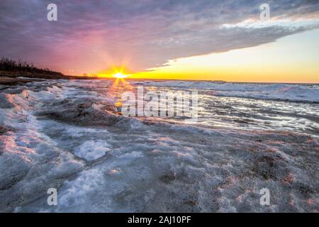 Michigan inverno Lago paesaggio. Raggi di sole illuminano la congelati icy costa del Lago Huron Michigan sui Grandi Laghi costa. Foto Stock