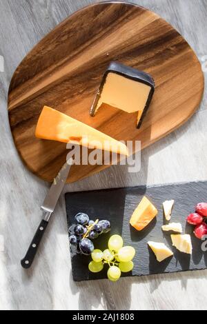Gastronomia a formaggio formaggio scheda e selezione di uve il pranzo. Rustico comfort food flatlay immagine. Rosso, bianco e nero uve organico con il rosso e bianco Foto Stock
