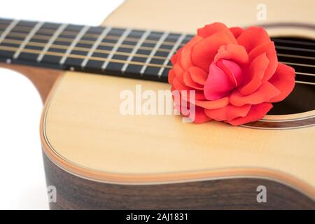 Canzone d'amore. Soft focus sognante immagine di una rosa rossa su una chitarra acustica. La musica romantica concetto. In prossimità dei bellissimi fiori in acciaio di qualità string f Foto Stock